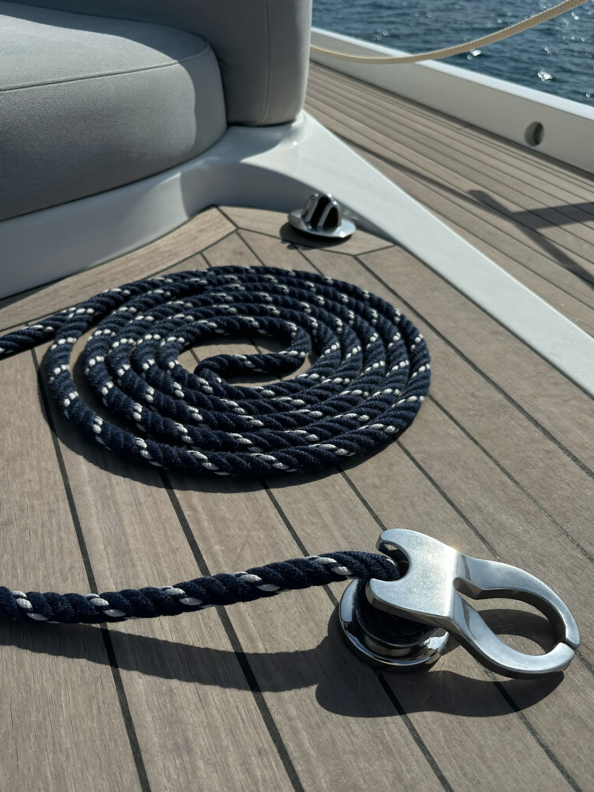Navy mooring line coiled on the teak deck of a yacht