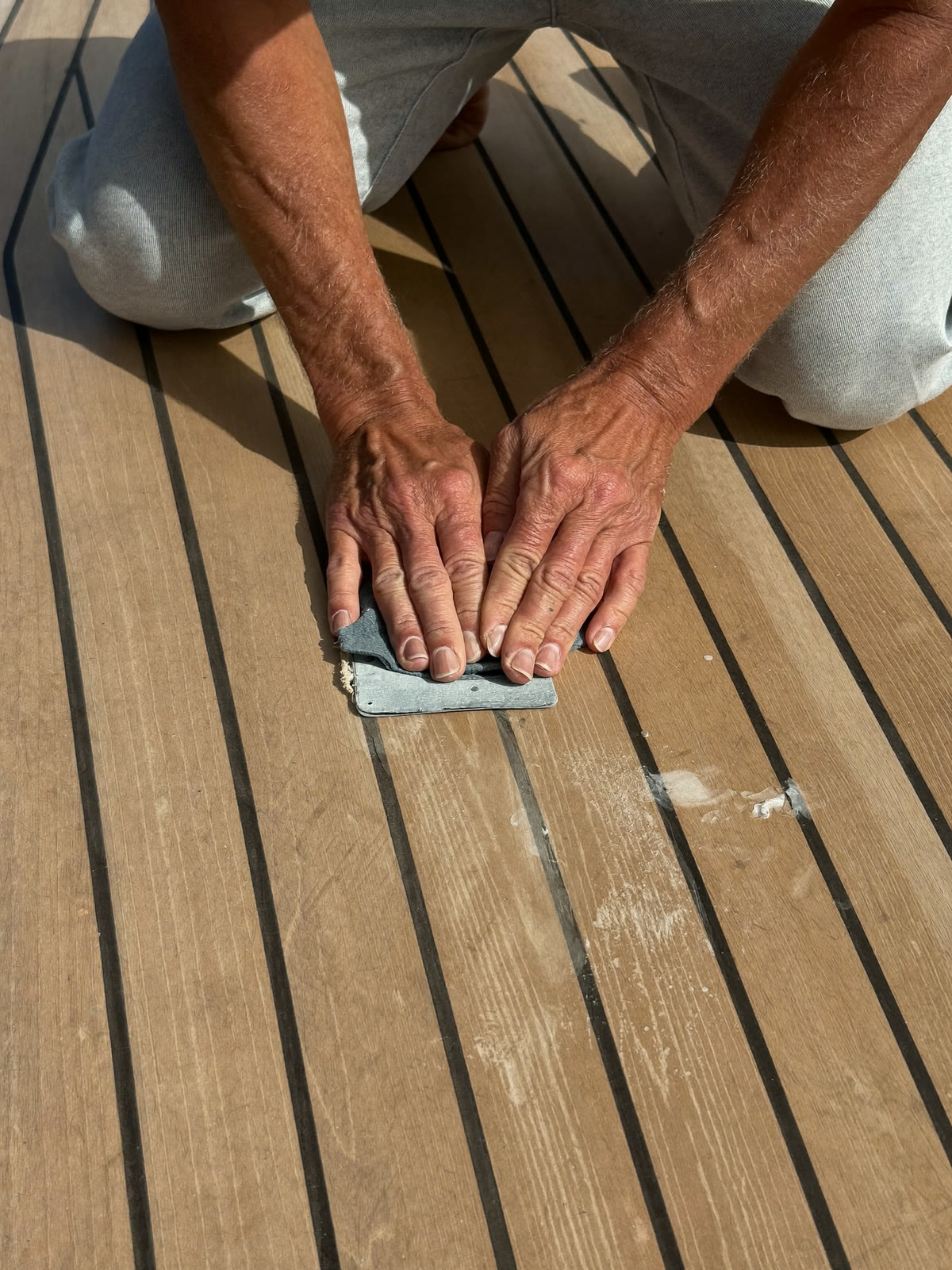 Craftsman sanding and treating a teak deck