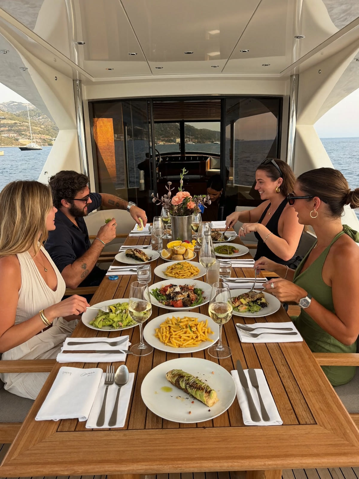 Gäste beim Mittagessen auf der beschatteten Flybridge einer ankernden Yacht