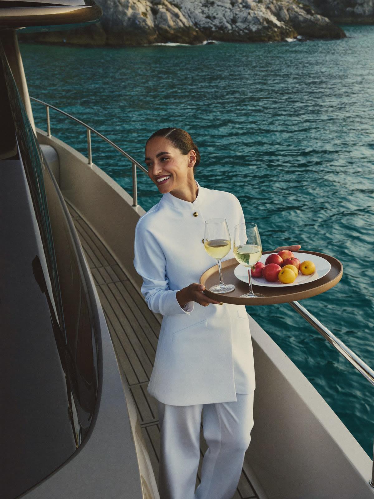 Hostess serving an aperitif on the aft deck of a yacht at anchor